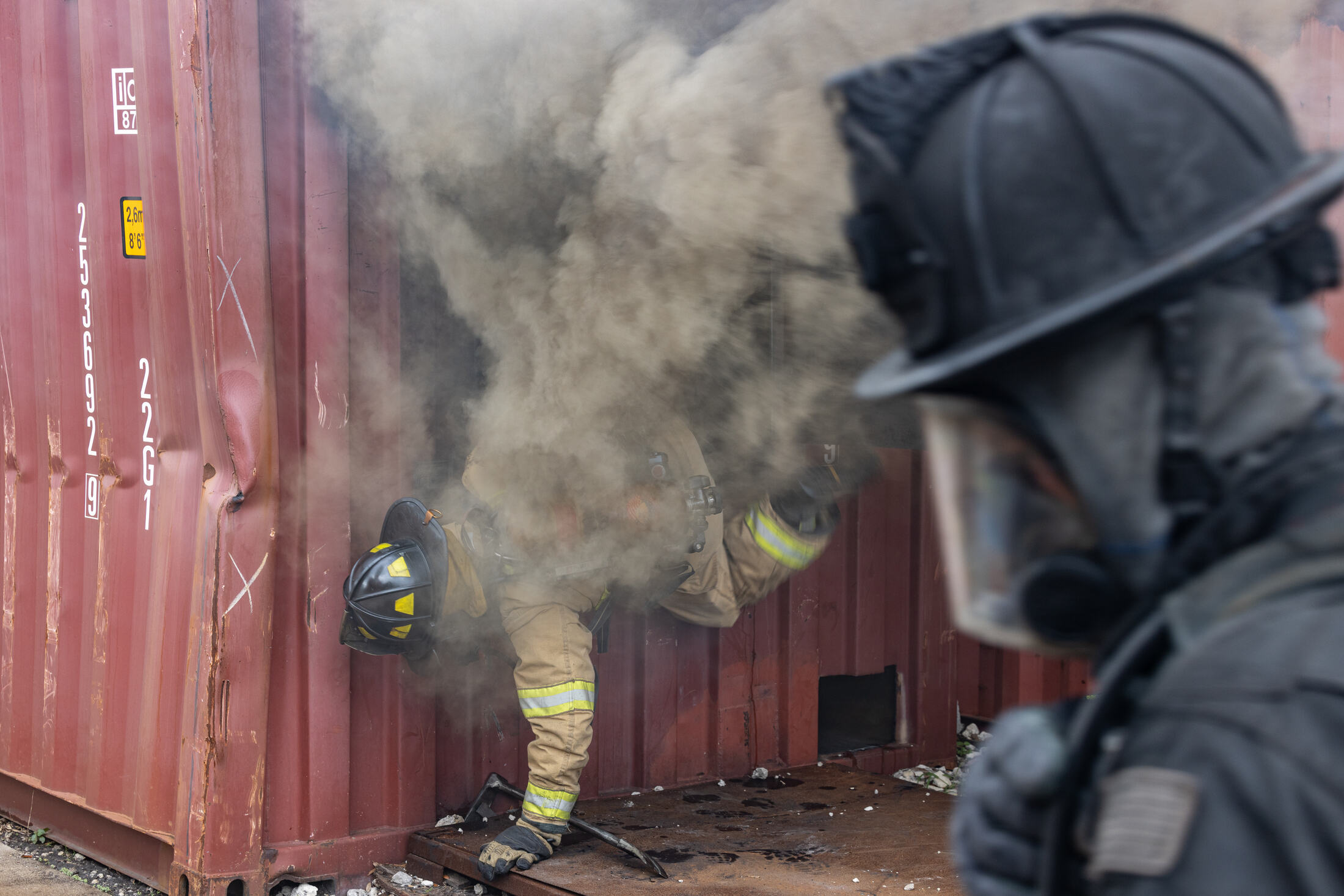 A firefighter walks through smoke and sunlight in a pine forest